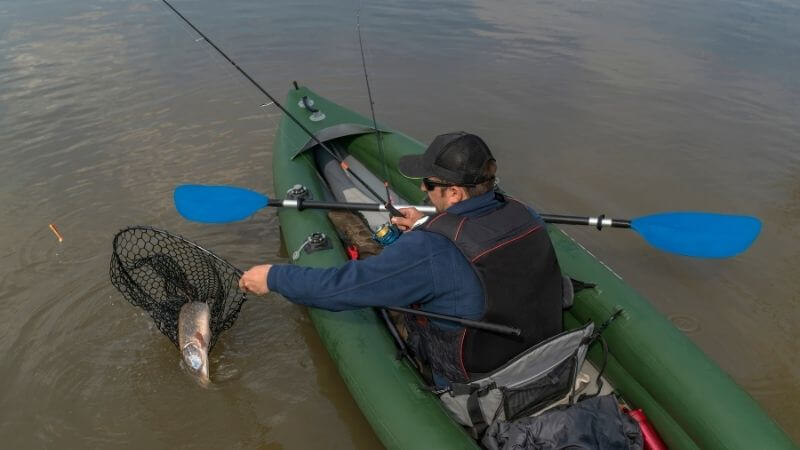 man catch a fish on kayak